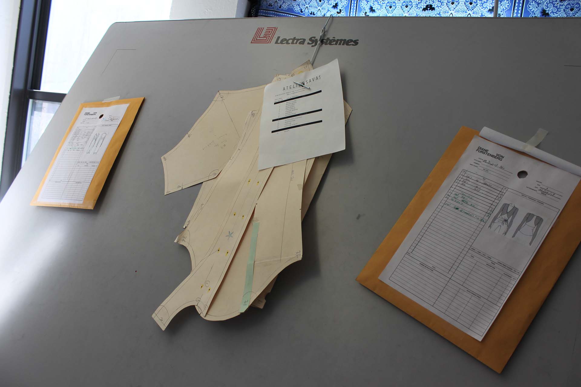Paper patterns and specification sheets hanging from Lectra systems digitizer table.