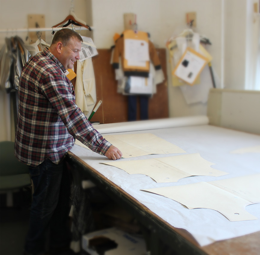 Anthony Cibelli placing paper patterns on top of graded plotter paper to test for quality control and consistency across the grade rules and sizing.