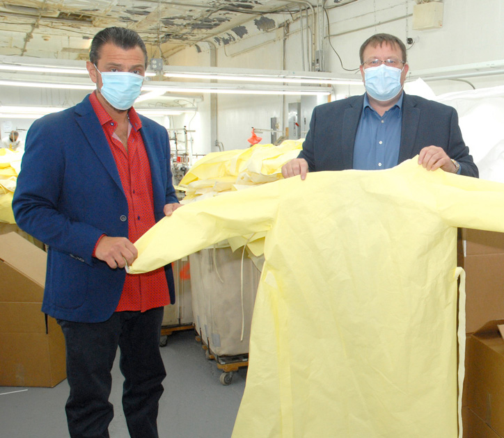 Anthony Cibelli holding a yellow isolation gown in factory manufactured in NYC for health care workers.