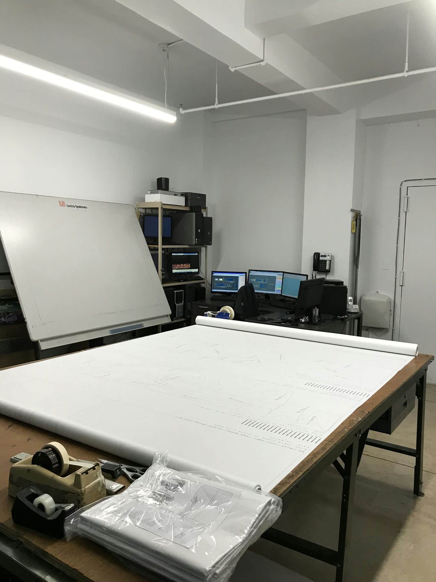 Top Notch Pattern NYC office showing Lectra systems digitizer table, printed marker on table, with digitizing and grading software open on computers on the background near servers.