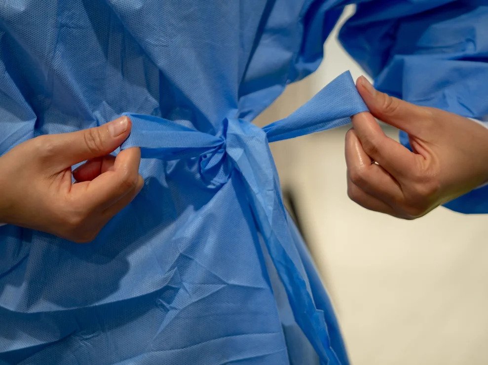 The back of a health care worker tying an isolation gown.