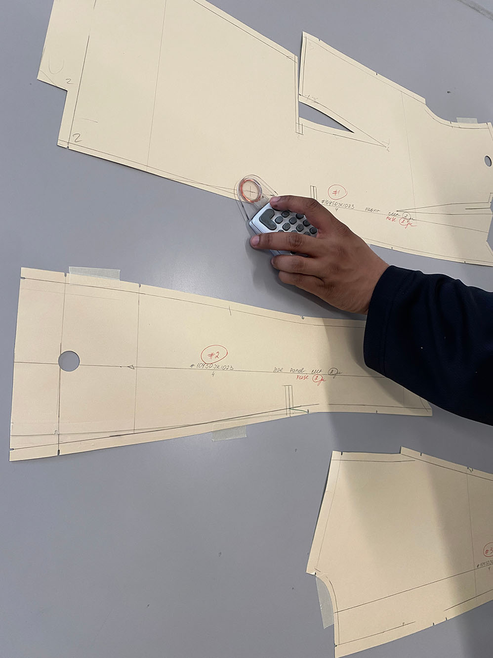 Close up of Top Notch employee manually digitizing paper patterns on digitizer table using a puck to meticulously trace and outline a paper pattern into CAD to be graded for customer.